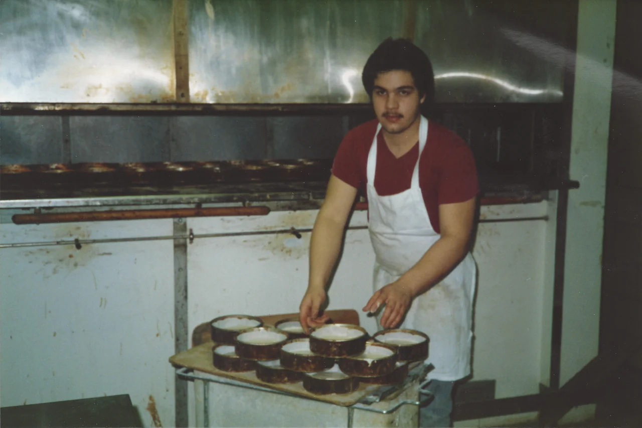 A photograph from the Fragapane family archive showing a baker holding pans beside the bakery ovens