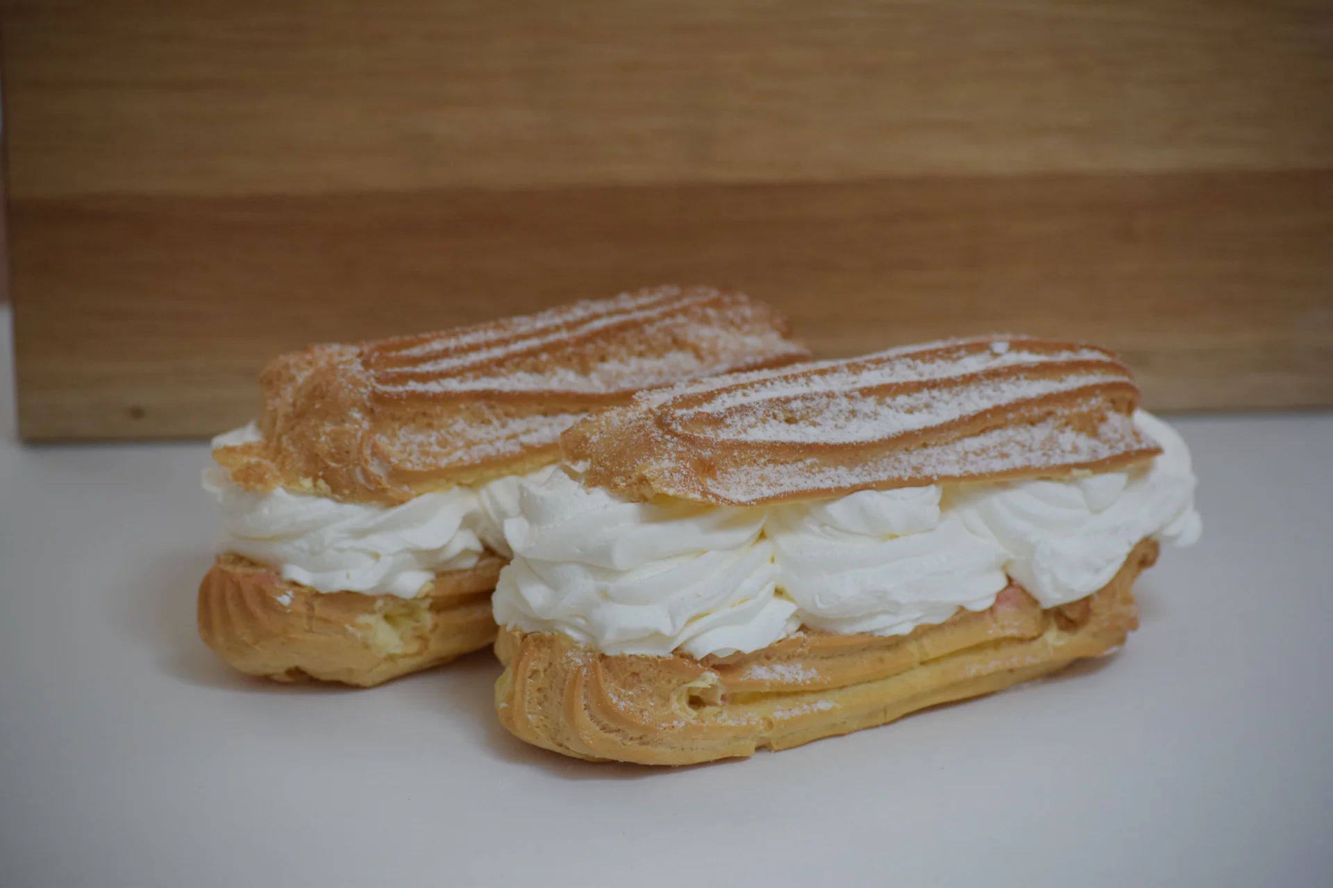 Two golden cream-filled pastries dusted with powdered sugar at Fragapane Bakeries