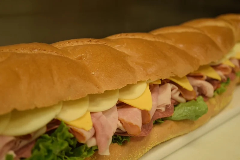 A deli sandwich filled with sliced meats, cheese, lettuce and tomato