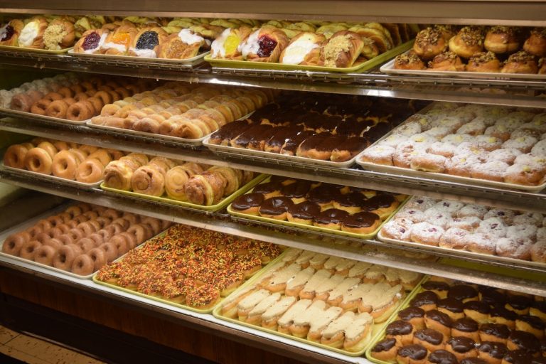 Bakery display case filled with trays of doughnuts and pastries