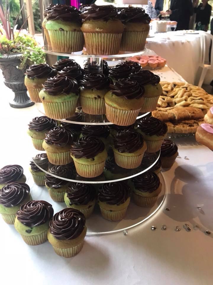 A tiered display of cupcakes topped with dark chocolate icing