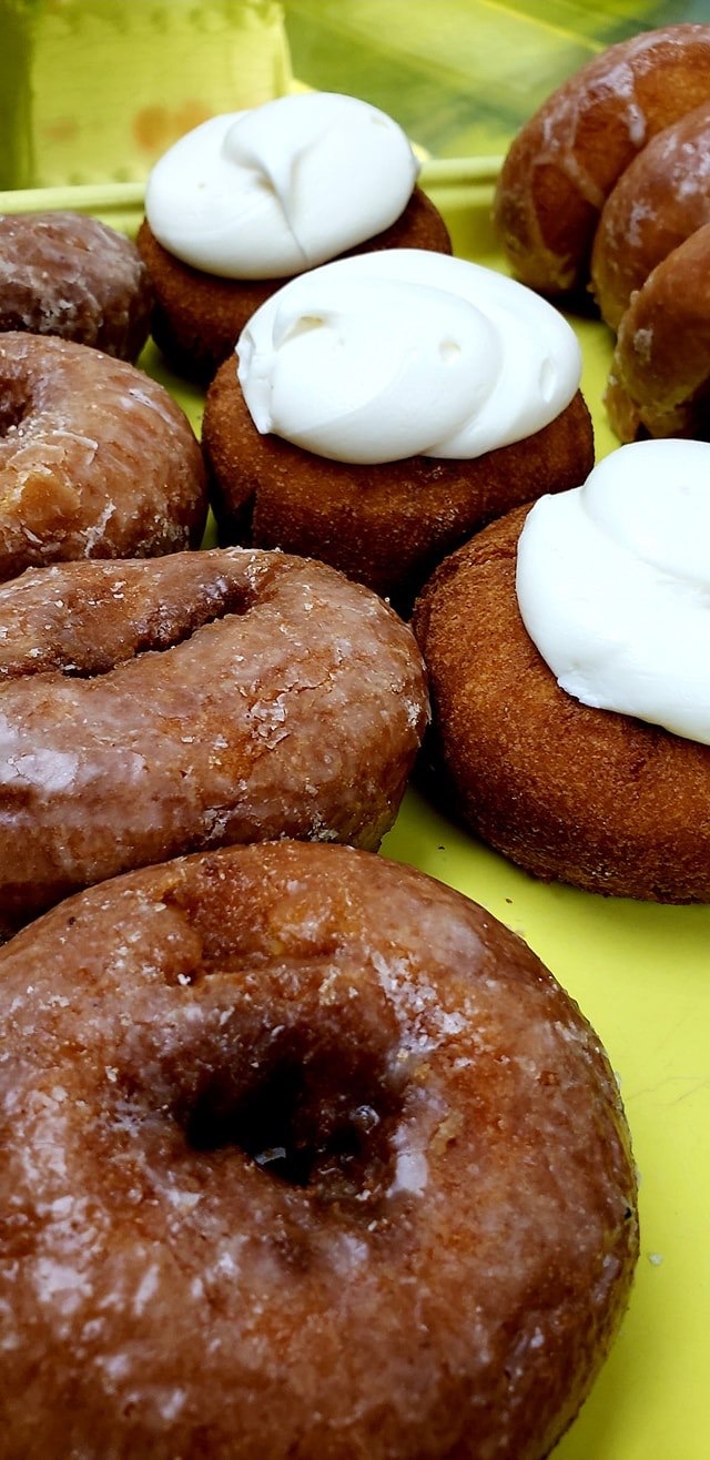 Glazed doughnuts and pastries topped with white icing in the bakery case