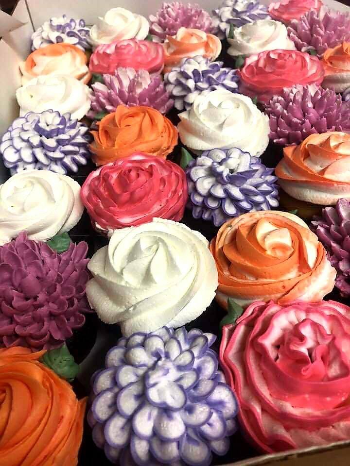 Cupcakes decorated with pink, orange, white and purple icing flowers